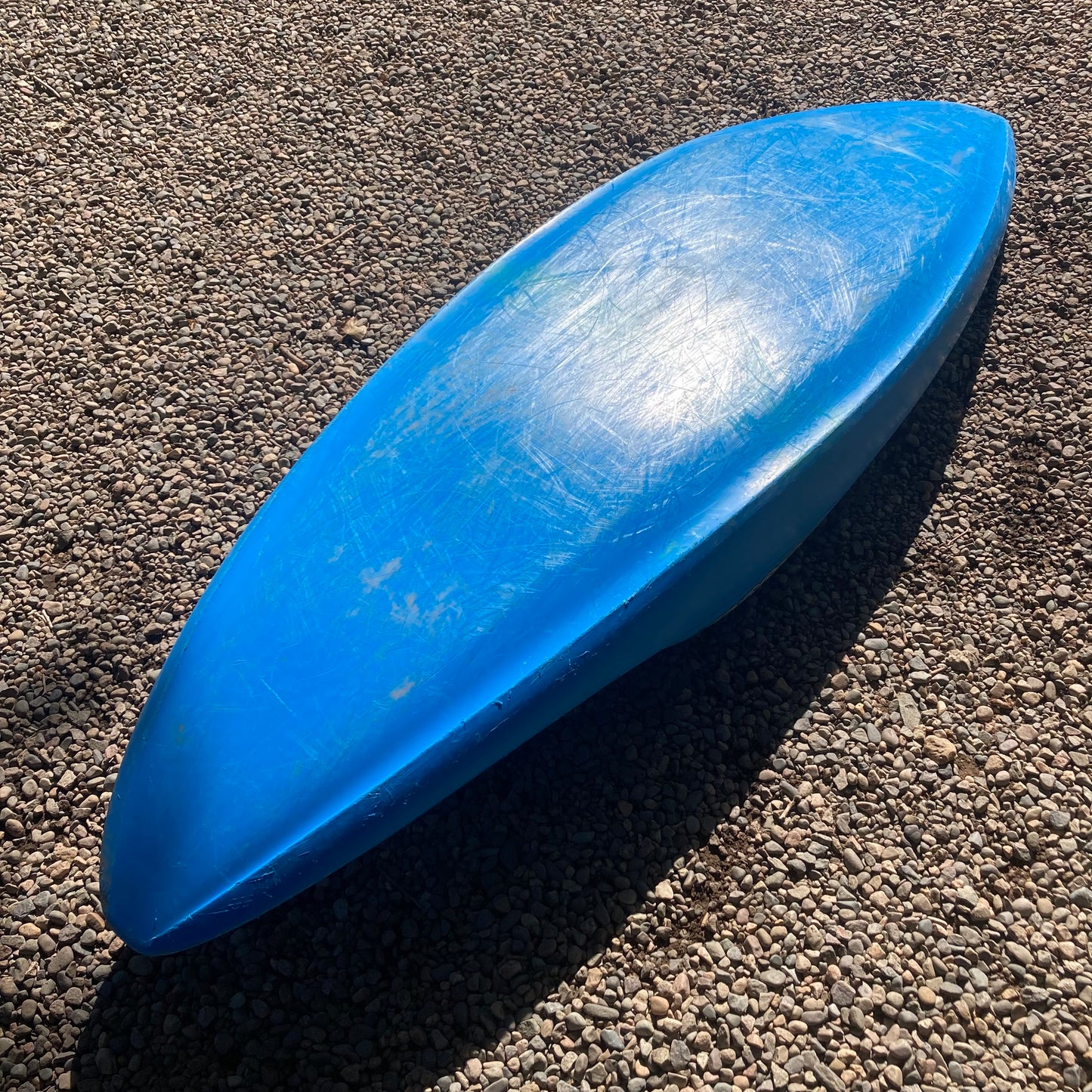 A blue Demo Supernova canoe laying on a gravel road by Dagger.