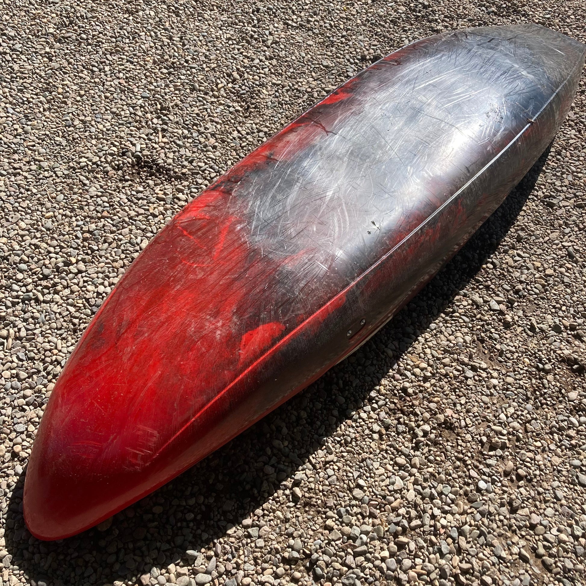 A red and silver Verus canoe laying on the ground.