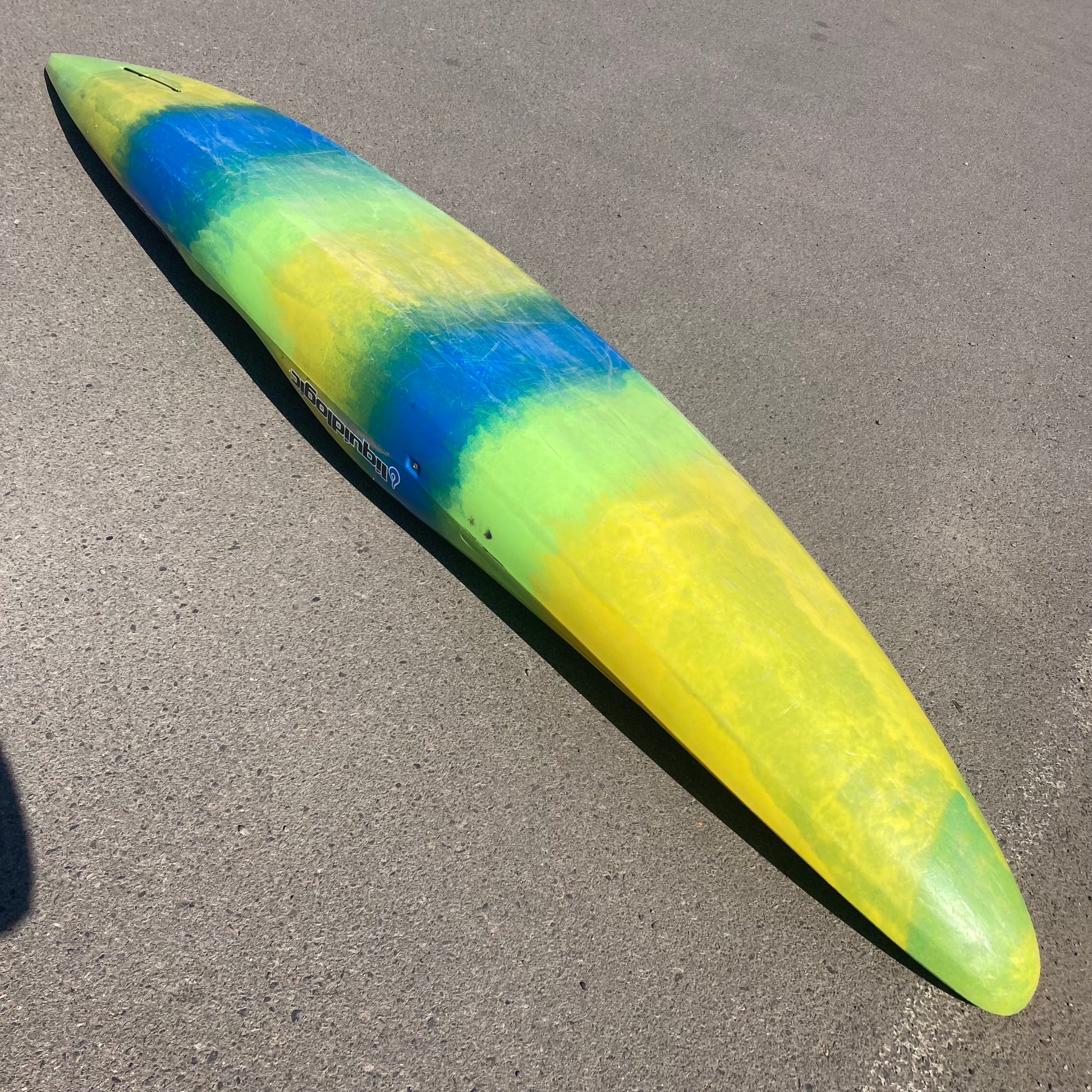 A yellow and blue Demo Stinger XP surfboard laying on the ground. (Brand: LiquidLogic)