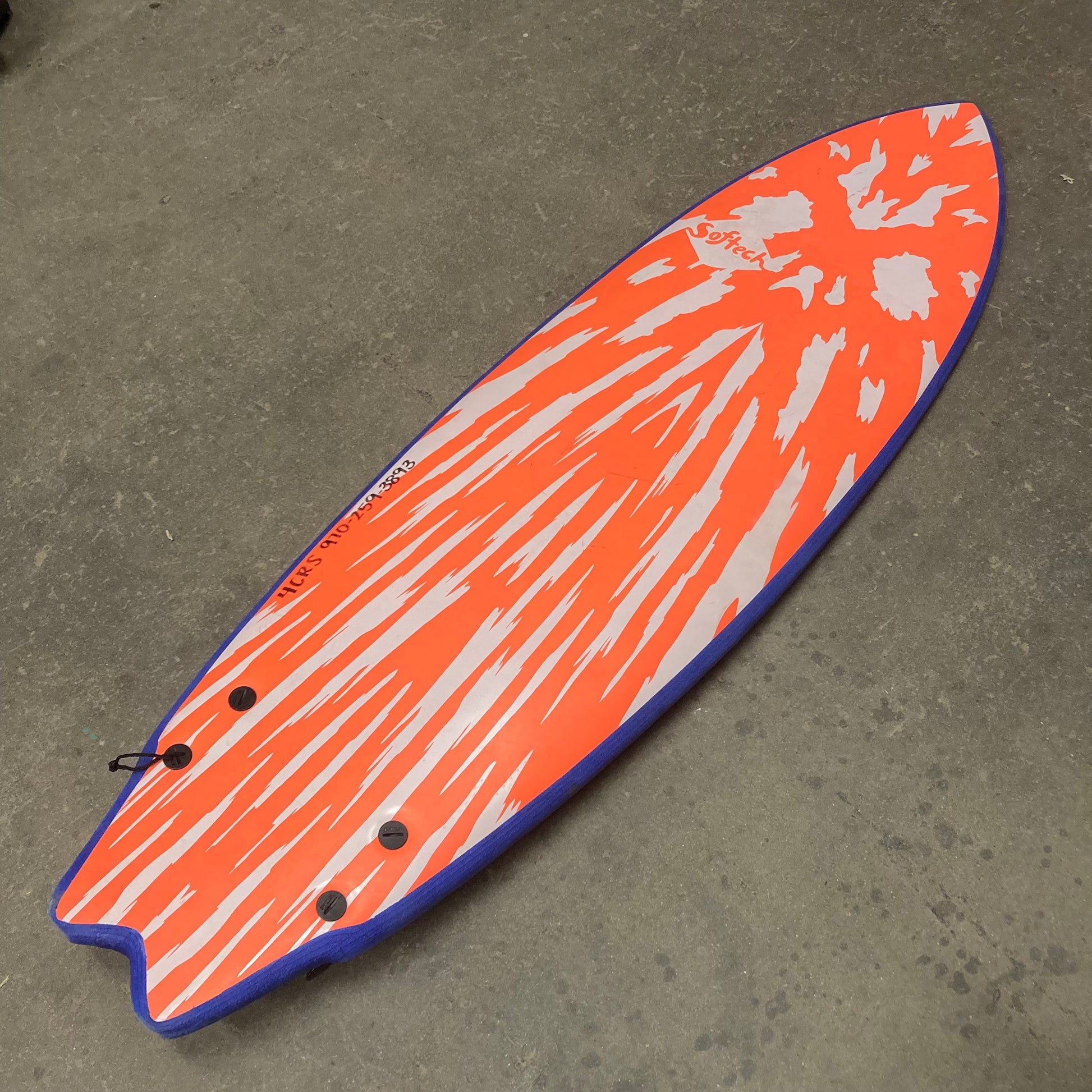 A Demo Mason Twin surfboard with an orange and blue design by FCS.