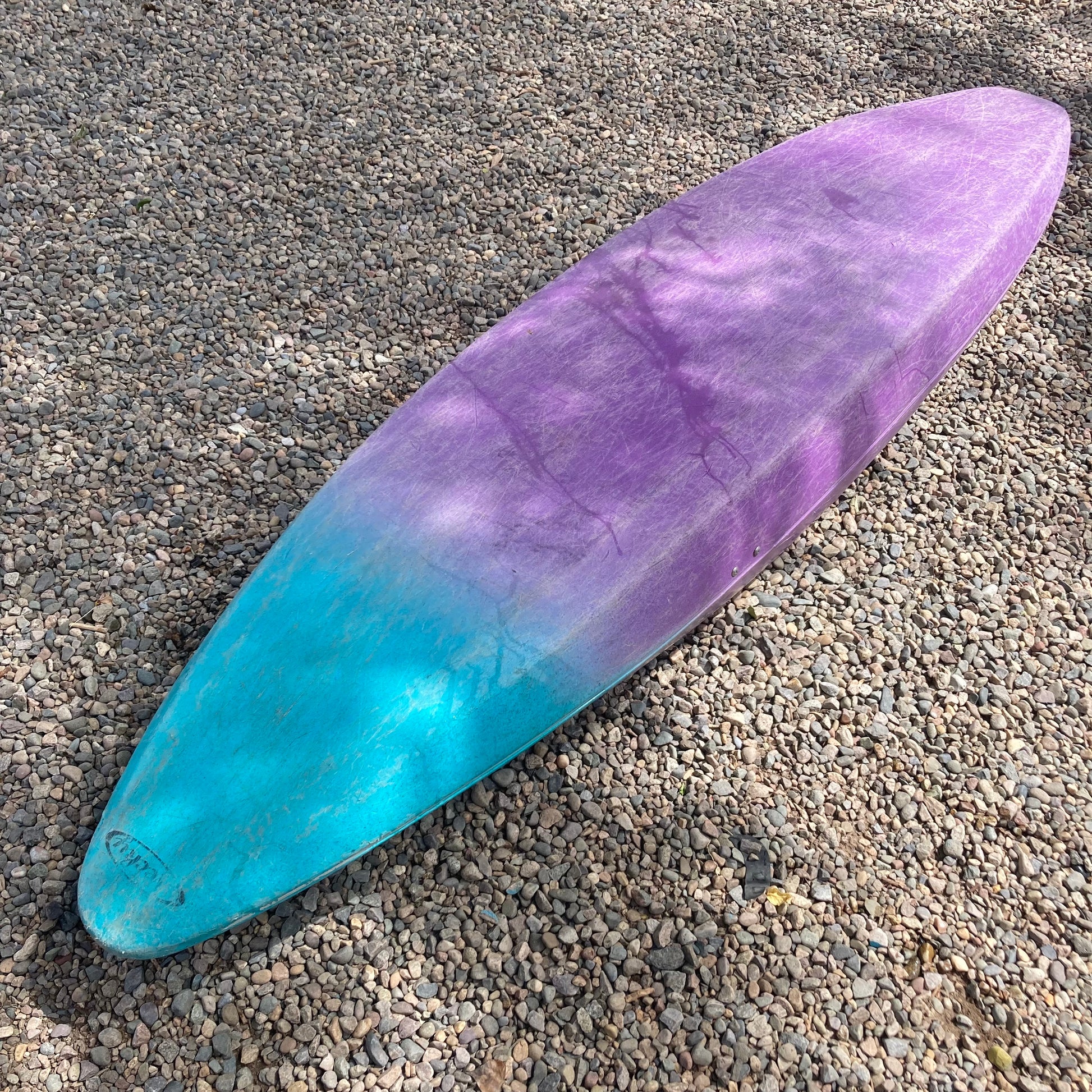 A purple and blue Consignment Necky Jive surfboard laying on the ground, made by 4CRS.