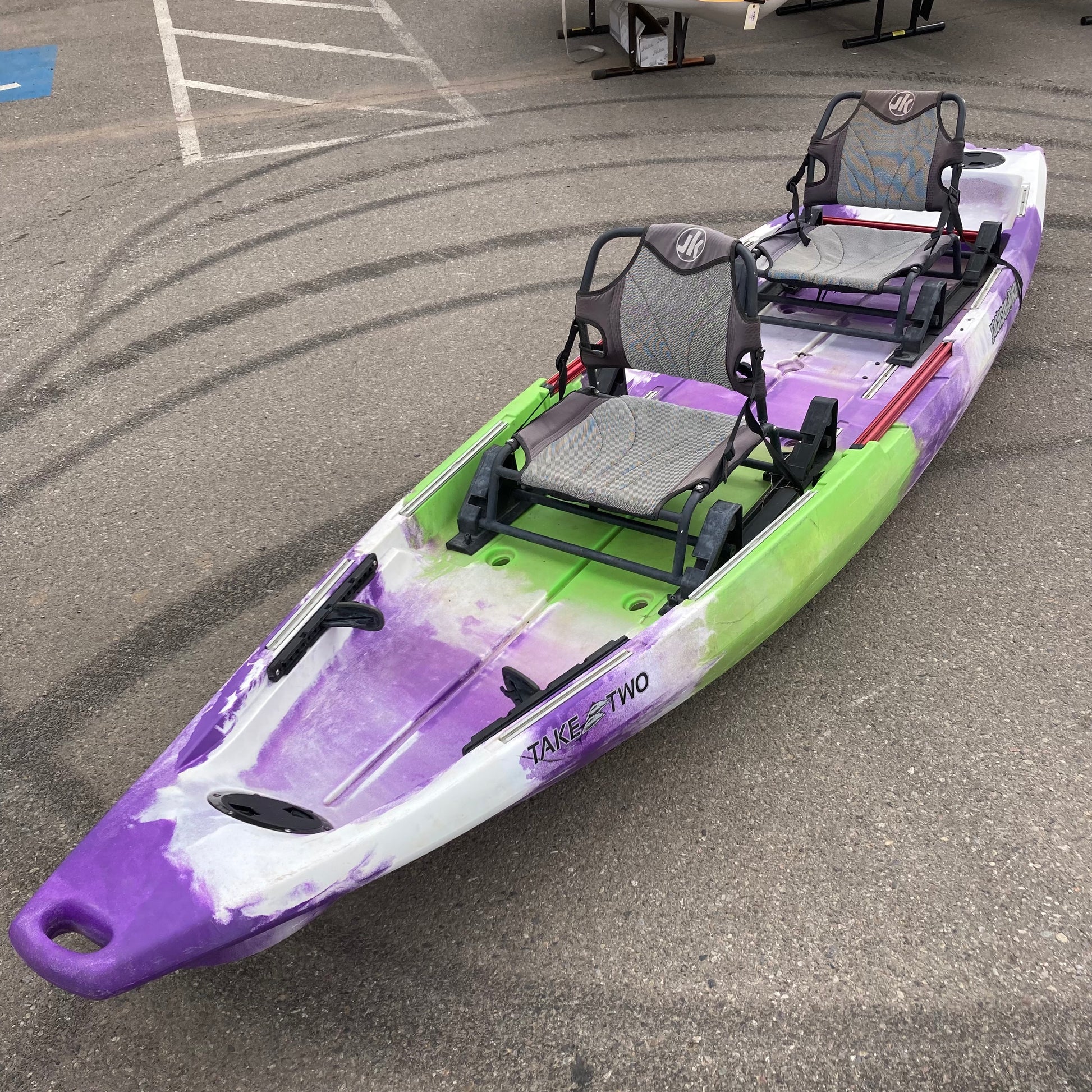 A purple and green Demo TakeTwo kayak is parked in a parking lot, branded by Jackson Kayak.