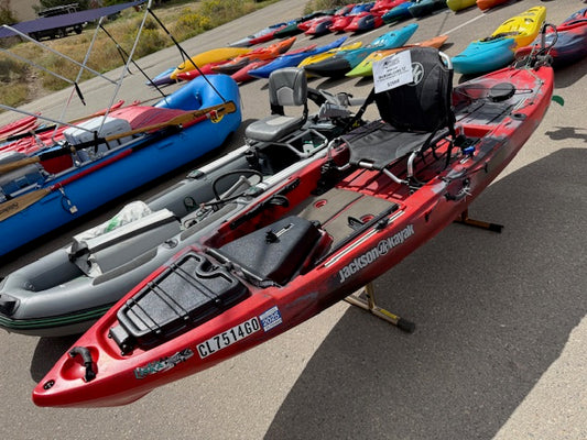 The Used Motorized Liska 12'1 by Jackson Kayak, equipped with a Newport NK300 motor, is shown outdoors among other boats—ideal for anglers seeking ready-to-go performance and adventure.