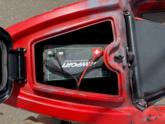 A used Jackson Kayak Liska 12'1 with Newport NK300 motor and a 36V 50AH battery (attached cables) is installed in the storage compartment of the red fishing kayak.