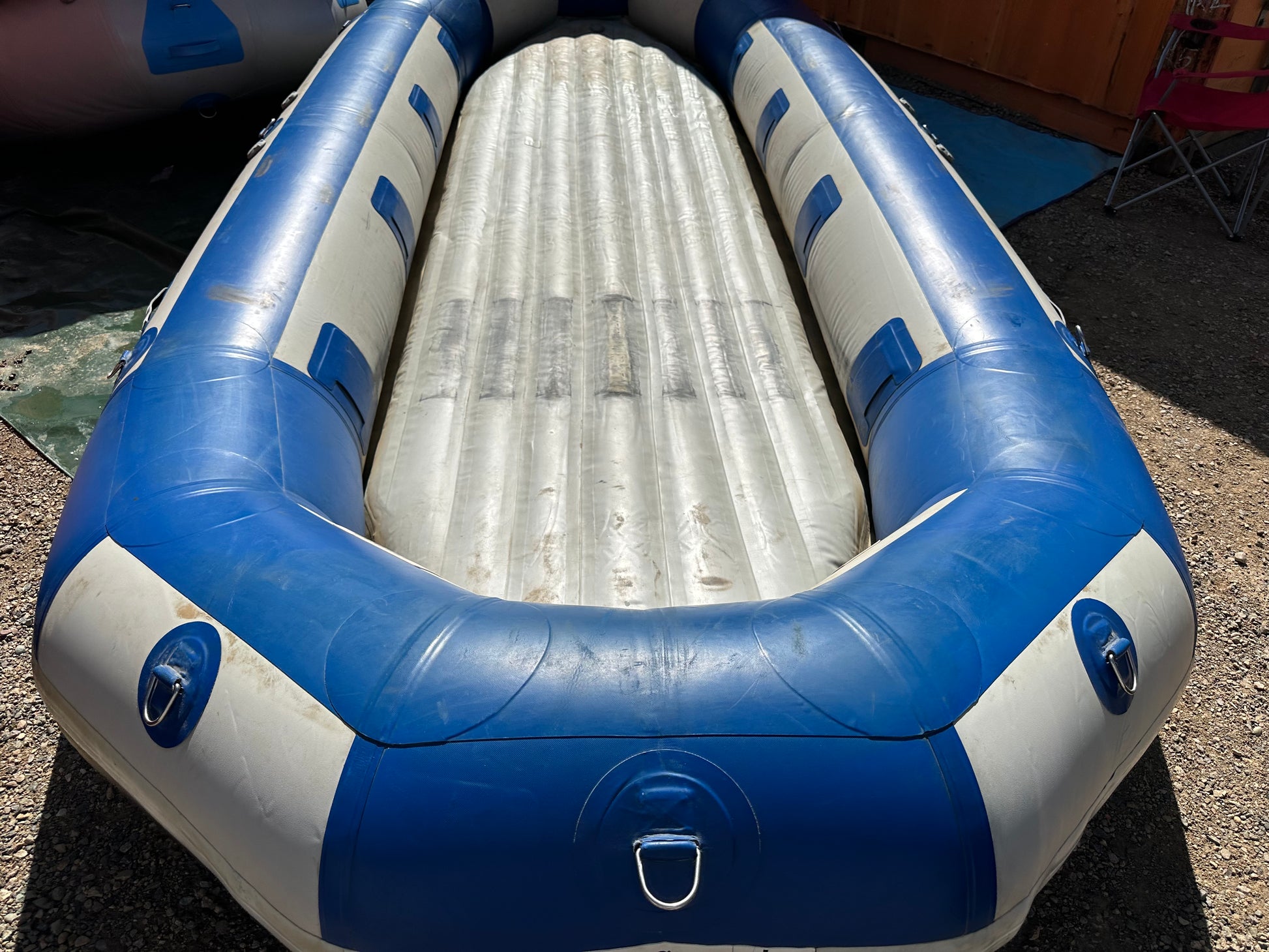 A used blue and white 16' 4CRS Vanguard raft in fair condition sitting on the ground.