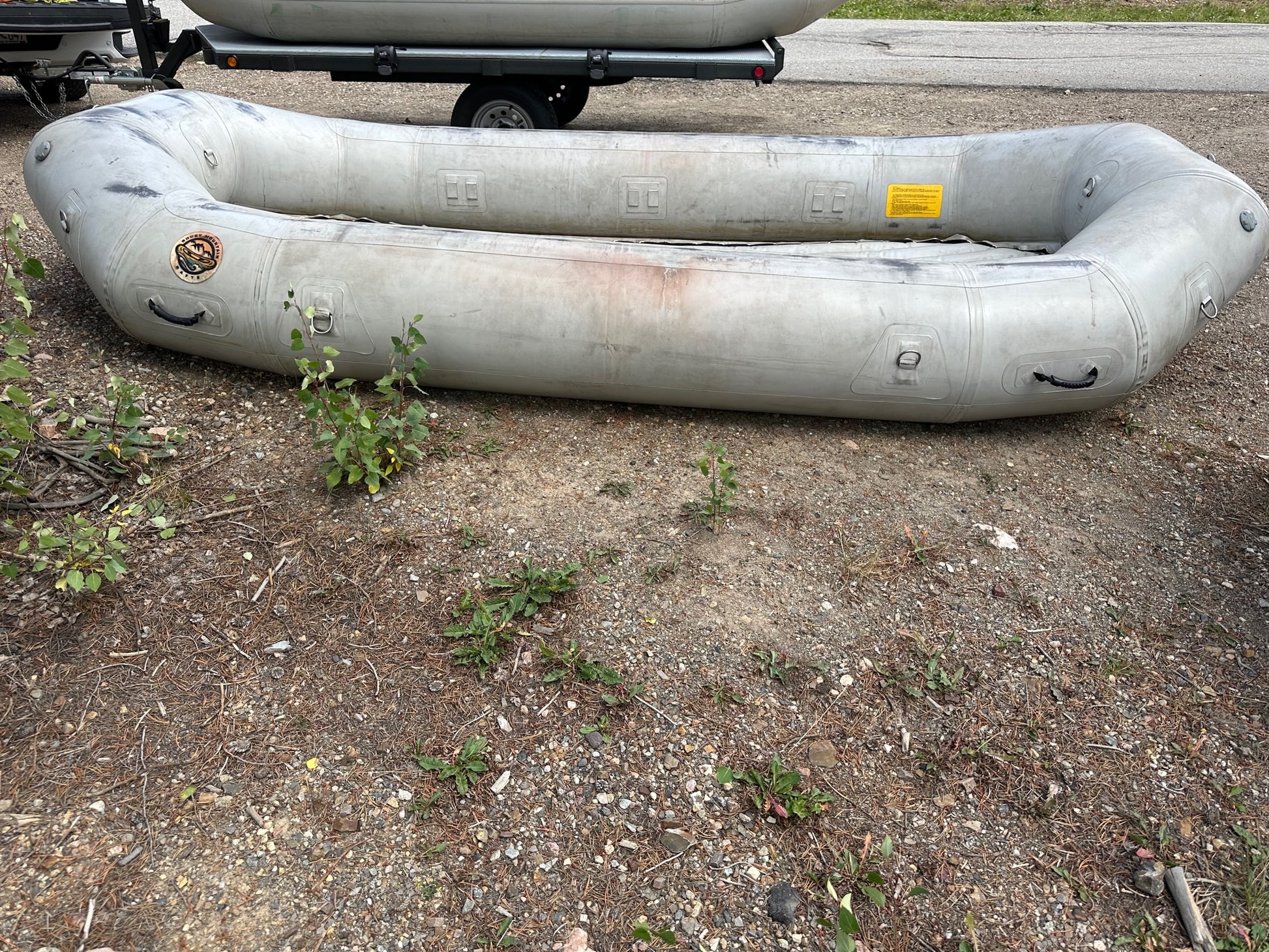 A Used 14' Rocky Mountain Raft in fair condition sitting next to a trailer.