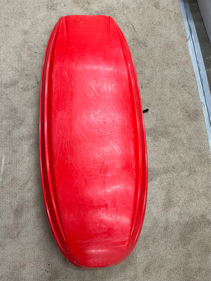 A Jackson Kayak Demo Rockstar V LG with visible scratches lies upside down on a beige carpet next to a metal strip, resembling a used kayak awaiting its next adventure.