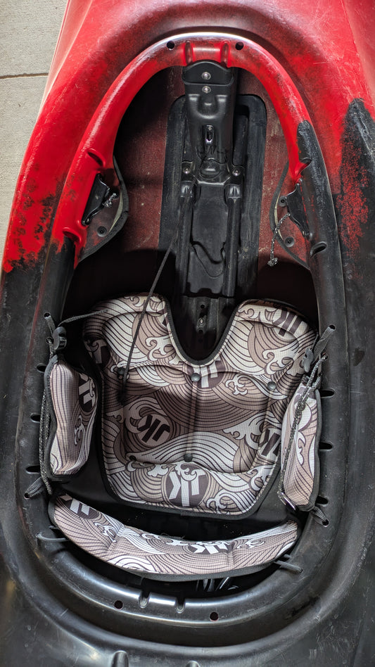 A close-up of the interior seating area of a red Demo Clutch 2025 by Jackson Kayak highlights its padded seat and patterned leg supports—ideal for anyone looking for a top-quality used kayak.