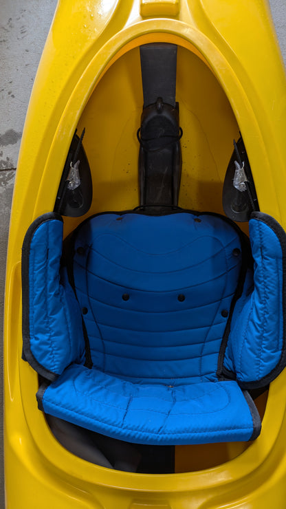 A close-up of the Demo Powerslide by LiquidLogic shows its yellow interior with a blue padded seat and black footrests.