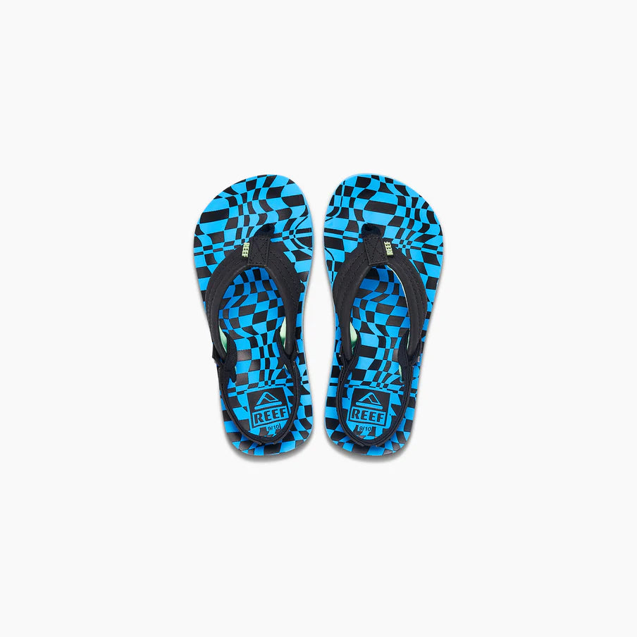 A pair of REEF LITTLE AHI children's flip-flops with black straps and blue and black geometric checkered soles, featuring a durable foam outsole, shown on a white background.