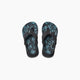 A pair of REEF LITTLE AHI children's flip flops in black with blue and black leaf-patterned insoles, featuring the REEF logo on the heel and a durable foam outsole, shown from above on a white background.