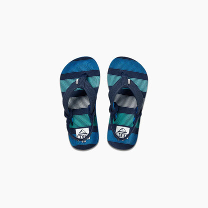 The REEF LITTLE AHI Children's Flip Flops feature navy blue straps and blue, teal, and white striped soles, with the Reef logo on the footbeds and a durable foam outsole for all-day comfort.