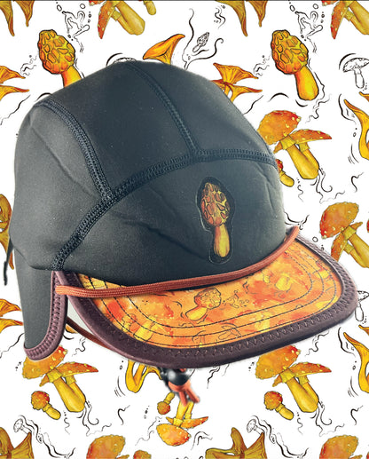 The Nobdody's Nobdody Flat Brim Skull Cap is a black five-panel cap with an orange mushroom pattern on the brim and front, shown against a backdrop with matching illustrated mushrooms.