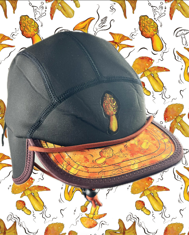 The Nobdody's Nobdody Flat Brim Skull Cap is a black five-panel cap with an orange mushroom design on the front and brim, shown against a backdrop of repeating mushroom illustrations.