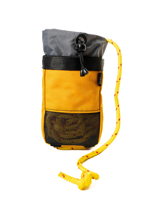 The River Station Gear PFD Throw Bag is a compact yellow and gray throw bag with a floating rope, black mesh pocket, and yellow cord strap, shown on a white background. Perfect for pairing with your Astral Rescue PFD.