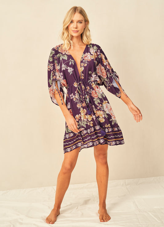 A woman wearing the Maaji Divinity Dress, a purple floral mini dress.