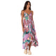 A woman models the Maaji Parrot Dress—a colorful, floral, sleeveless maxi with a handkerchief hem—paired with beige platform shoes, set against a white background.