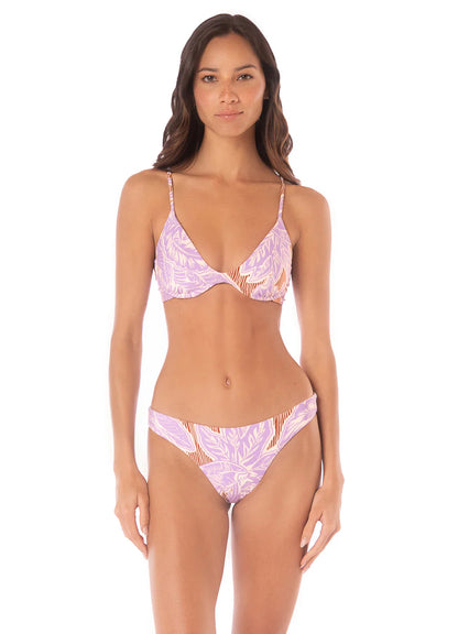 A woman stands facing forward against a white background wearing the Maaji Sublimity Bikini, featuring a lavender and orange pattern with a low-rise, reversible swim bottom.