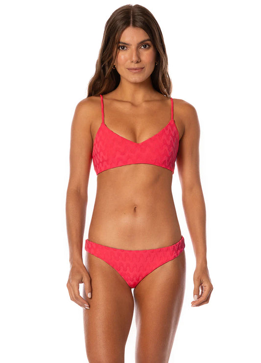 A woman stands facing forward against a plain white background, wearing the Maaji Rocks Top—a red bikini featuring a subtle zigzag pattern.