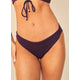 A person wears the Maaji Sublimity Bikini—a dark purple, reversible, low rise bottom with matching top; image focuses on torso and upper thighs.