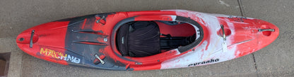 A Used Pyranha Machno whitewater kayak from 4Corners Riversports, featuring a red and black design, rests on a concrete surface as seen from above.