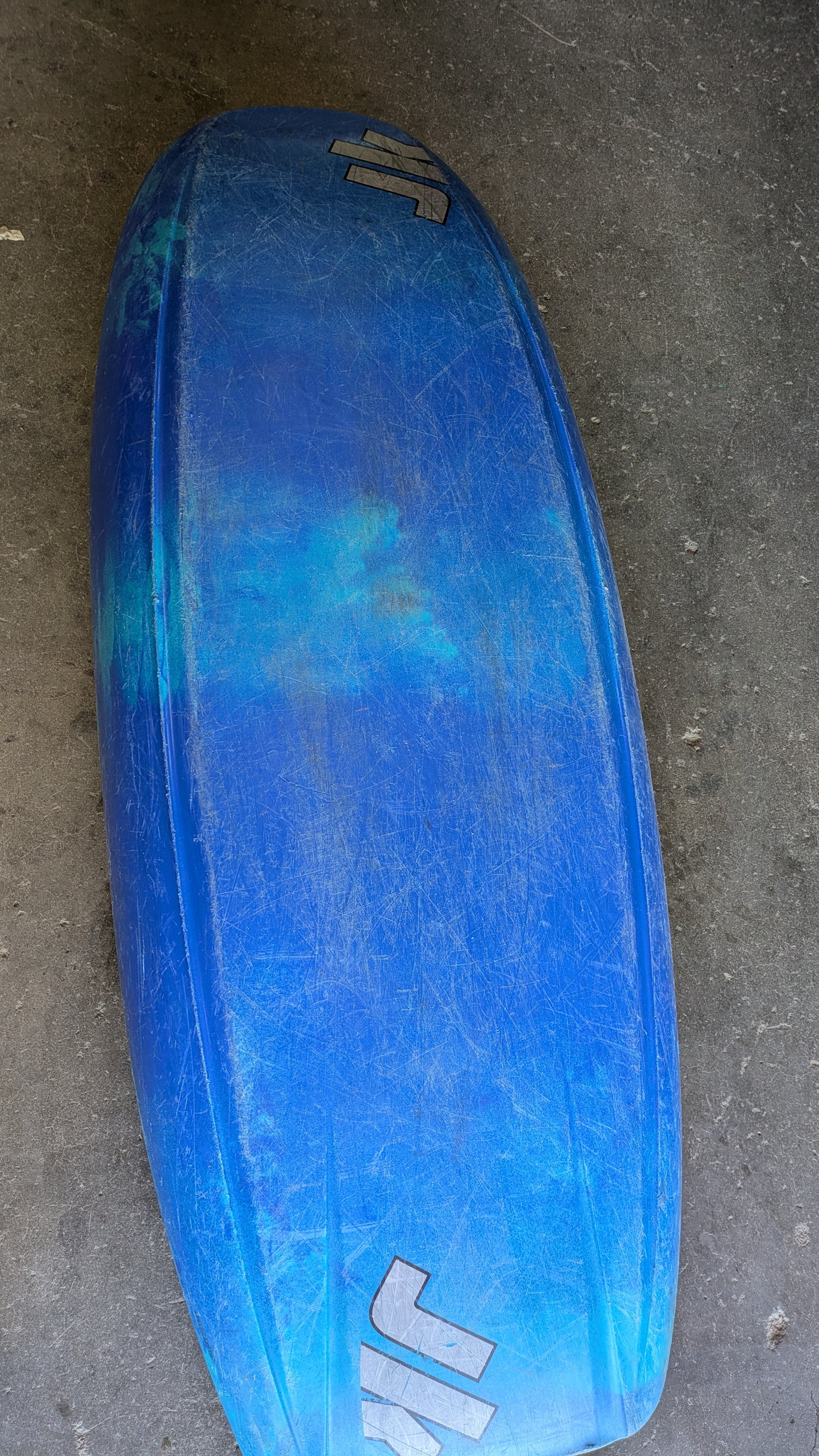 A Consignment Medium Jackson Rockstar 3.0 freestyle kayak from 4Corners Riversports is displayed upside down on a gray concrete surface, with visible scratches and three white logos.