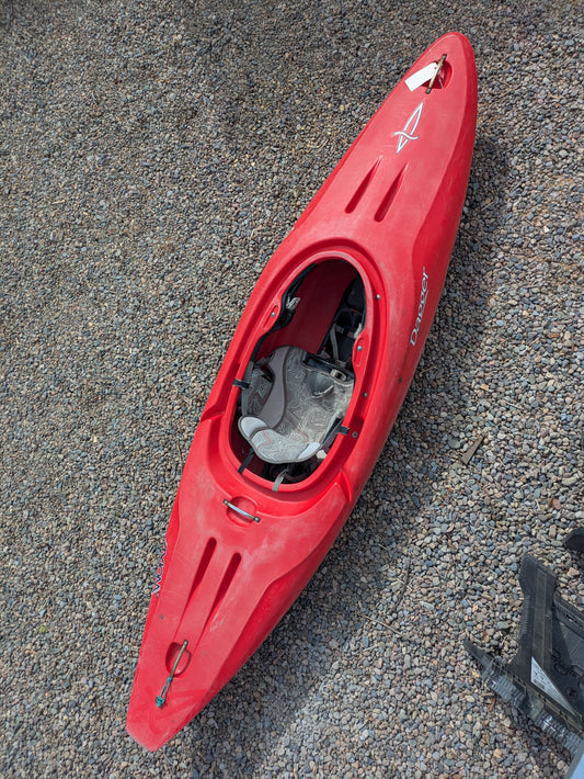 The Consignment Dagger Axiom 9.0 kayak by Dagger, featuring a red hull and gray patterned seat, is shown resting on gravel as seen from above.