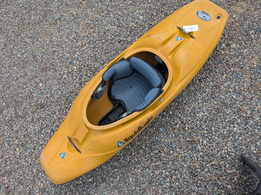 A Wavesport Consignment LiquidLogic CR125 river runner kayak with a padded seat is resting on a gravel surface.