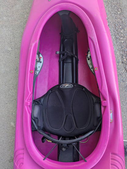 Top-down view of a Consignment Pyranha Burn 1 - Small Pink kayak from 4Corners Riversports, featuring a black padded seat and foot braces, shown on concrete—perfect for developing paddling skills.