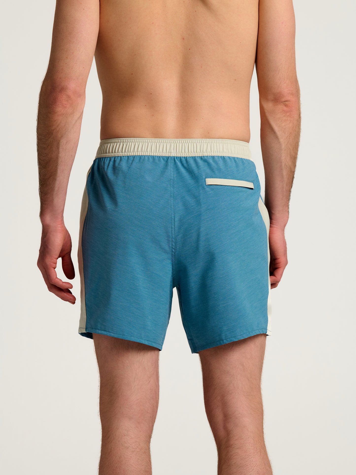 Back view of a person wearing Free Fly Palmera Boardshorts M's in blue, featuring a beige waistband, quick-dry fabric, and a single back pocket, set against a plain light background.