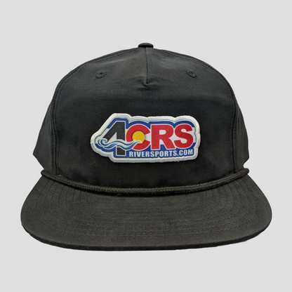The 4CRS Pops Hat by 4CRS is a modern black snapback with a front patch reading "4CRS Riversports.com," featuring wave and sunset embroidery.
