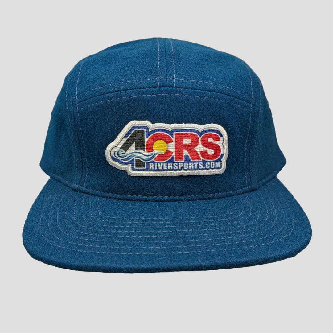 A blue "4Corners Riversports" wool cap with a patch displaying "4CRS Riversports.com" in colorful letters and a stylized wave design.