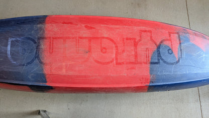A used Pyranha Demo Scorch X kayak, red and blue with a partially visible upside-down "Outworld" logo on the bottom. Shows scratches from prior use—could have been a demo boat.