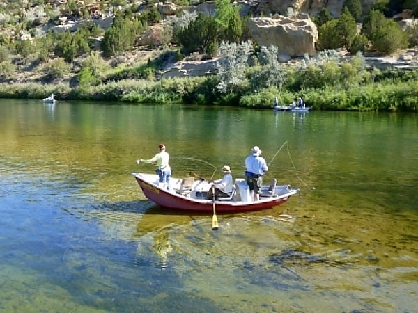 a group of men standing on top of a boat in a river.
