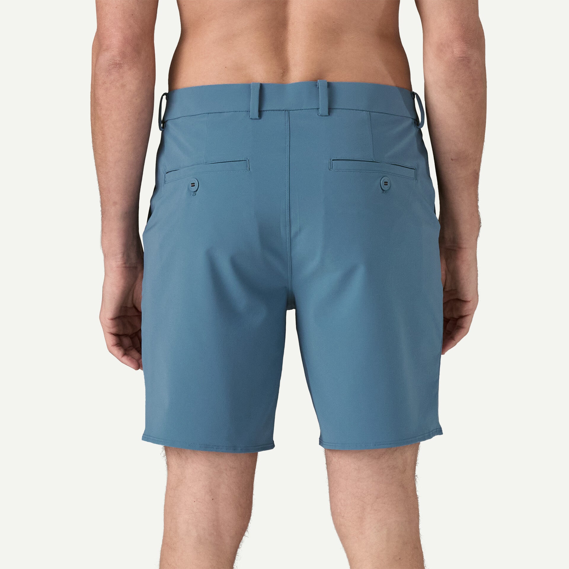 Rear view of a person wearing Patagonia's Hydropeak Hybrid Walk Shorts - 18 in., Fair Trade Certified™ blue knee-length shorts featuring belt loops and buttoned back pockets, against a plain background.