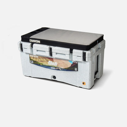 A rectangular gray portable cooler lid branded with "Canyon Coolers" features a printed image and silicone cup holders for convenience.
