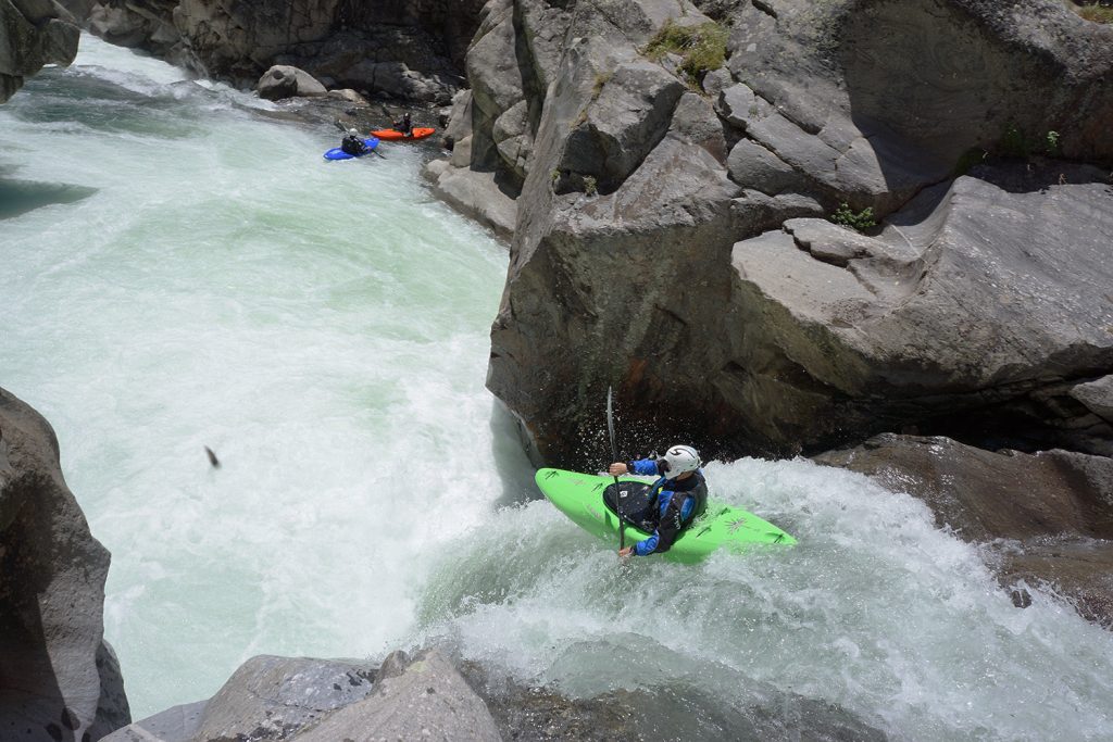 a man riding a green kayak on top of a river.