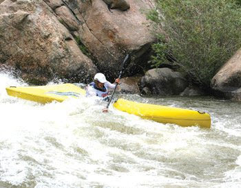 a man in a yellow kayak paddling down a river.