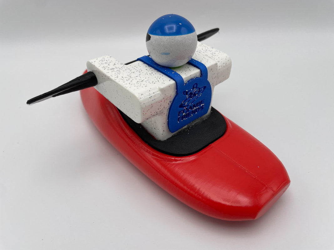 A toy robot from the Foamie Friends collection is featured in a red Foamie Play Boat, showcasing a white body, blue headgear, and black arms against a white background. This adventurous figure is designed to explore exciting river dynamics with its vibrant design and unique style.