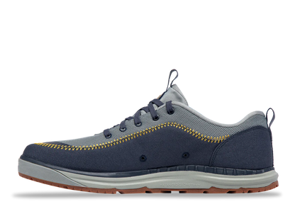 The Astral Brewer 3.0 features a side view of a blue and gray sneaker with yellow stitching, a gray sole, and brown tread. Made from hydrophobic canvas, it serves as a stylish yet functional water shoe.