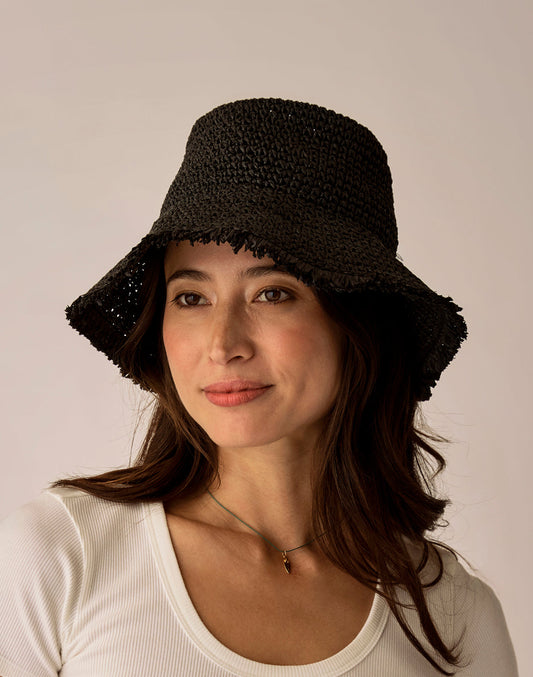 A woman in the Carve Farrah Packable Hat and a white ribbed top gazes to the side with a neutral expression against a plain background.