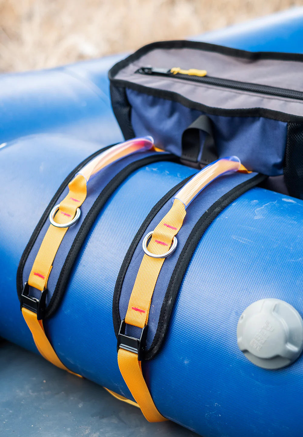 A close-up of a blue inflatable raft with a River Station Gear Thwart Bag - Rafting Mesh Gear Bag, featuring a YKK zipper, secured on top.