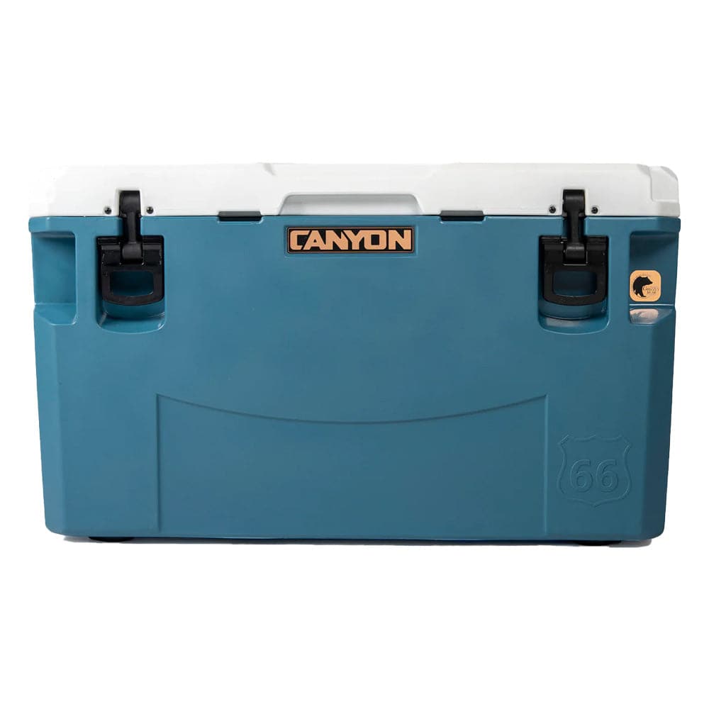 The blue and white PRO Series Cooler by Canyon Coolers, featuring black latches and a Route 66 logo, offers maximum ice retention and comes with a lifetime warranty, ensuring endless adventure.