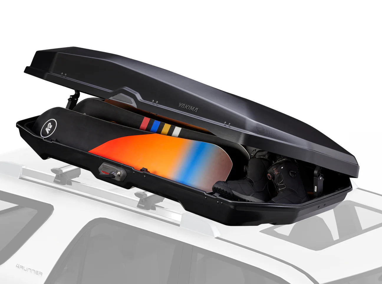 The CBX 16 from Yakima is open, showcasing a snowboard and boots neatly organized inside. This stylish cargo box, mounted on the car's roof, provides generous storage space for your adventure gear.