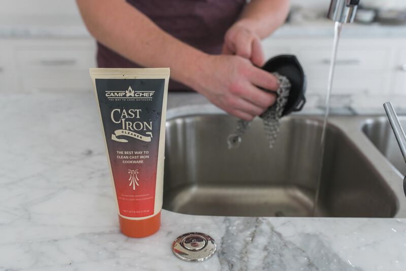 A man washing his hands in a sink with a tube of Camp Chef Cast Iron Care.