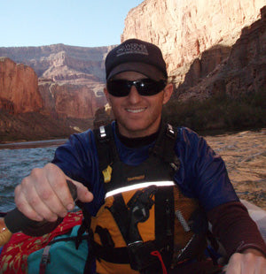 a man in a kayak pointing at the camera.