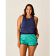 A person smiling while wearing a Carve Tide Tank and green shorts against a neutral background.