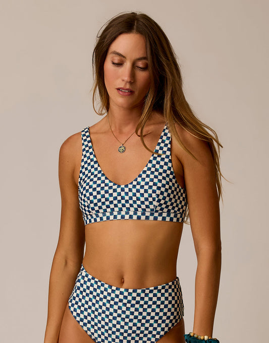 A woman models the Carve Breakers Compression Top bikini, featuring blue and white checks and high-waisted bottoms, against a plain background.