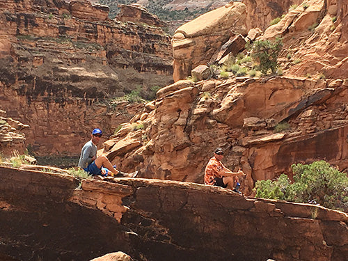 a couple of people sitting on top of a cliff.