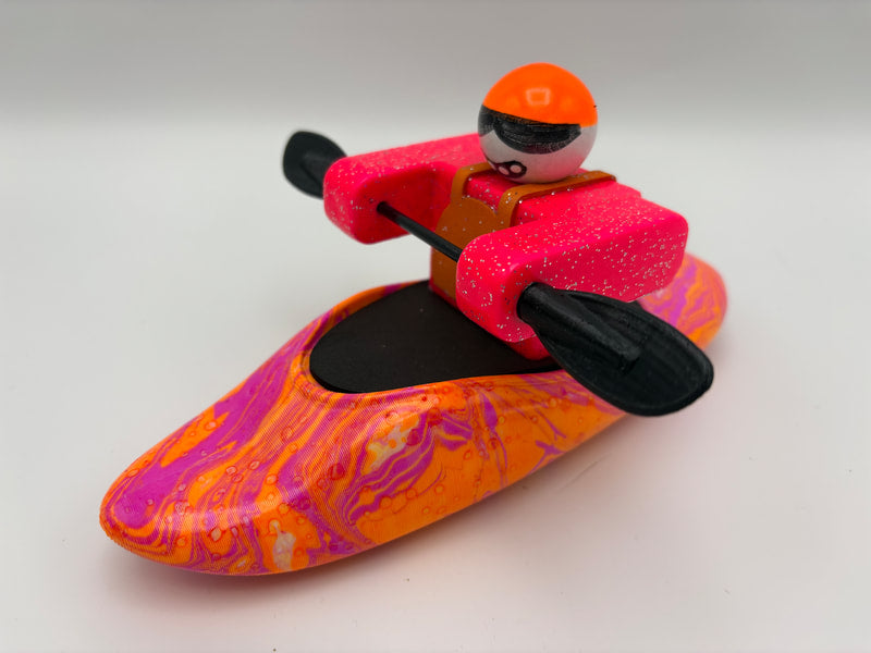 The Foamie Friends Swirl Play Foamie Boaters features a toy figure in bright pink gear with an orange helmet, sitting in a colorful plastic boat and holding a black double-bladed paddle—ready for fun adventures.